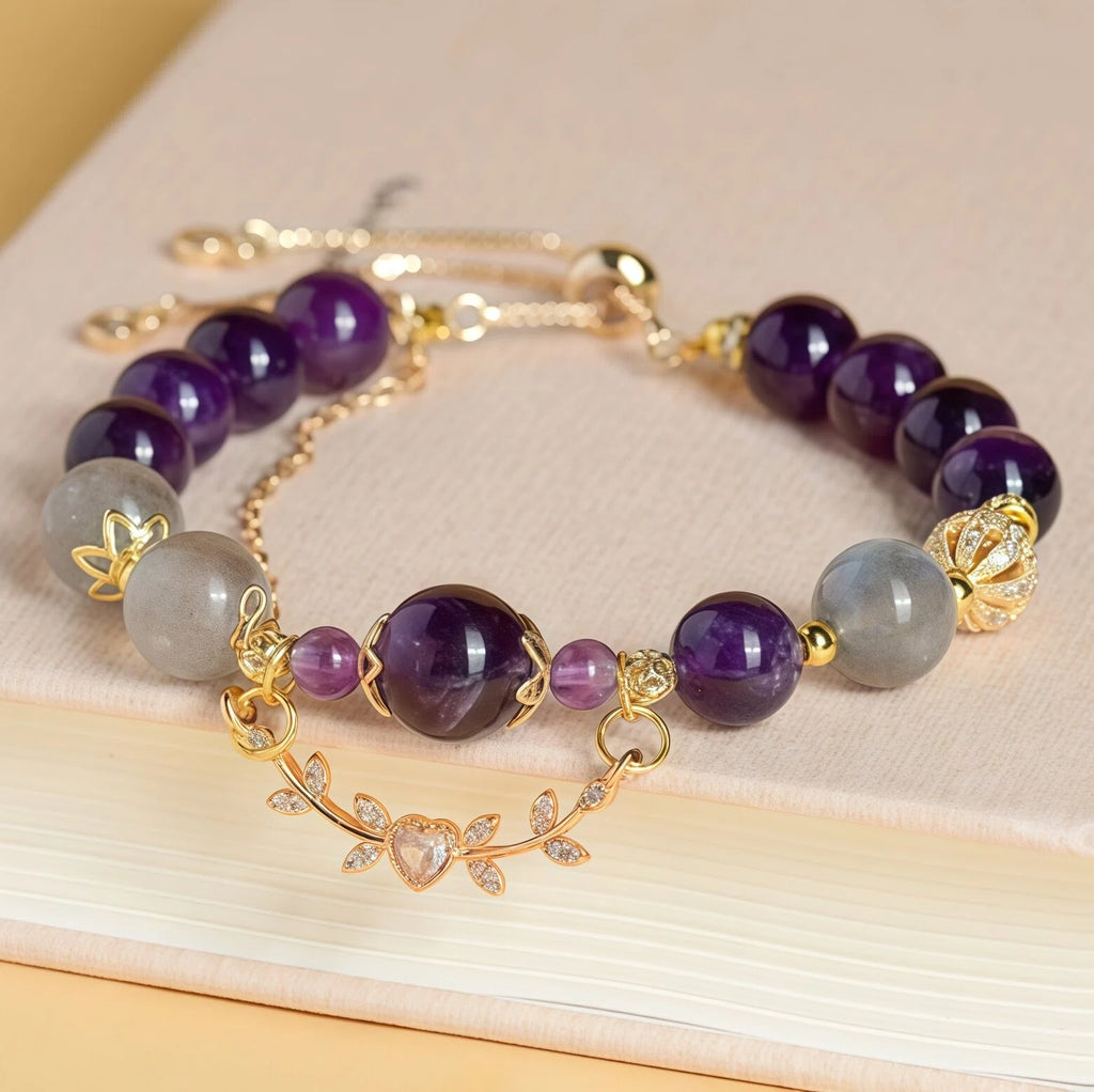 Styled flat lay of Scorpio Zodiac Bracelet resting on a book. Featuring Amethyst and Labradorite (Grey Moonstone) beads with a gold crystal vine charm for transformation - Kosmos Zen