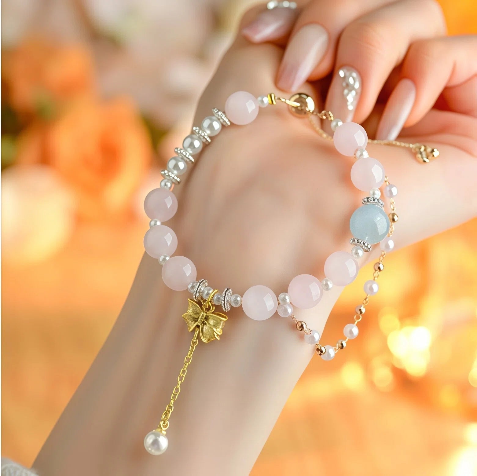 Elegant on-hand view of Virgo Zodiac Bracelet featuring 10mm Aquamarine and 9mm Rose Quartz beads. Delicate details of the gold Bow charm and 5mm Pearl accents worn on the wrist - Kosmos Zen